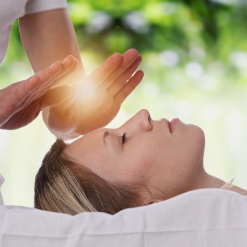 Woman having reiki healing treatment , alternative medicine concept.